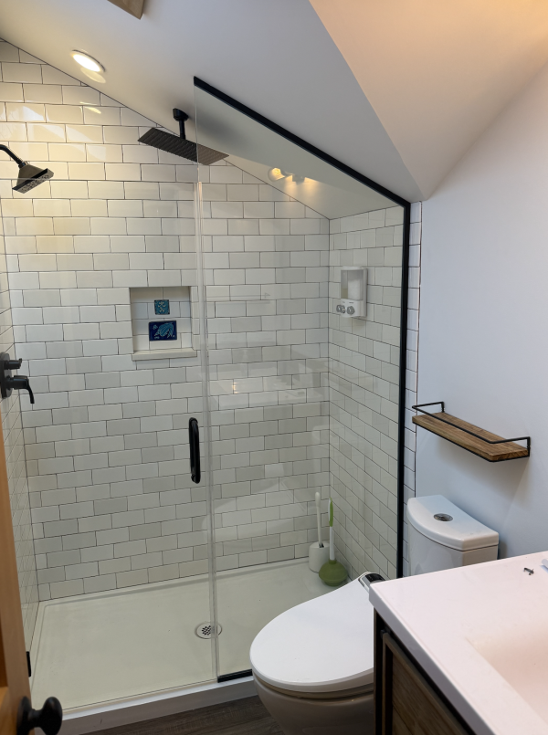 Screenshot 2025-09-30 at 8.33.49 PM Angled glass piece on sliding glass doors of bathroom shower.